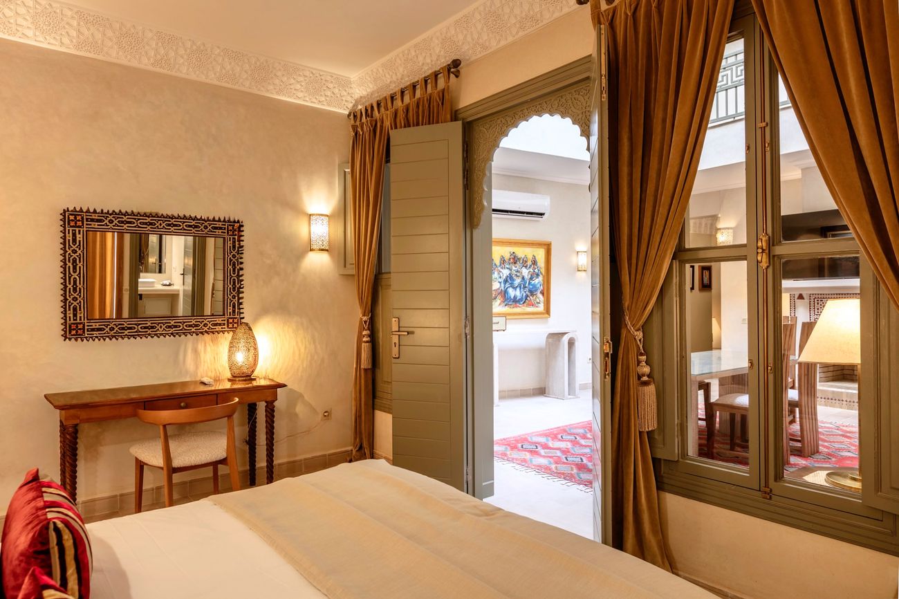 A bedroom looking through to the patio, with a carved mirror, writing desk and lantern light