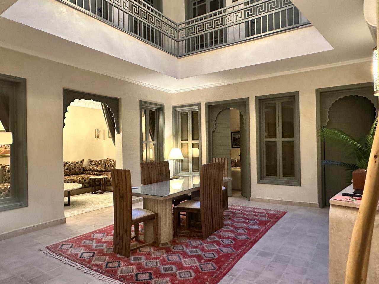 The dining table laid on a red Berber rug in the glazed patio, the salon through the archway