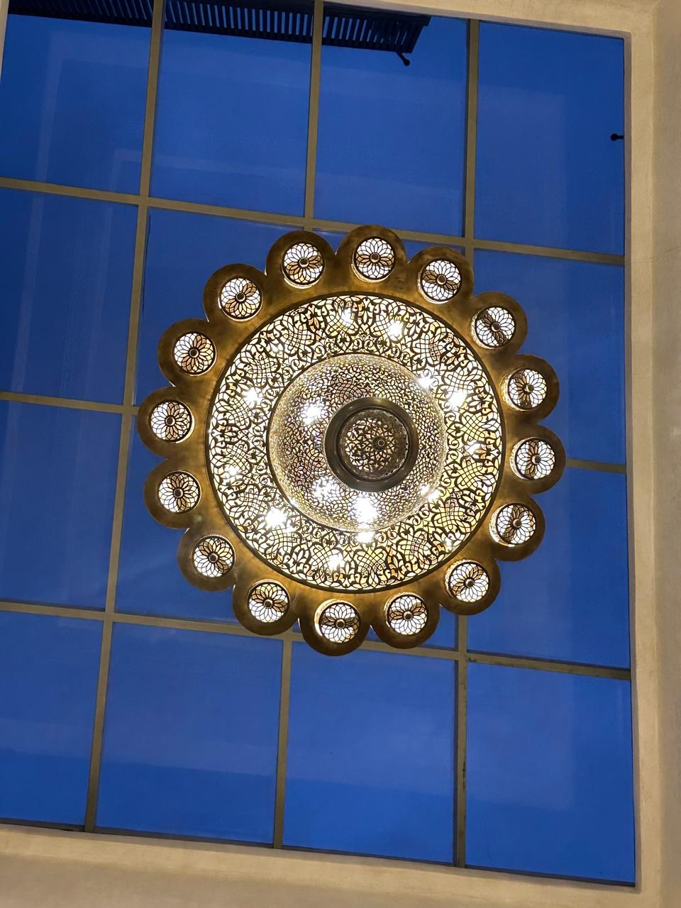 The glass roof of the patio with a brass chandelier hanging beneath it