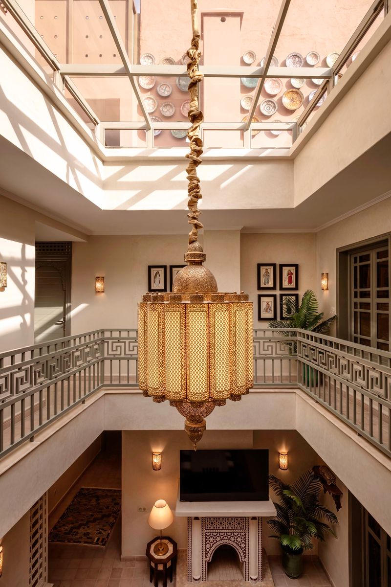 The patio from the upper gallery, the chandelier hanging past the skylight toward the fireplace below