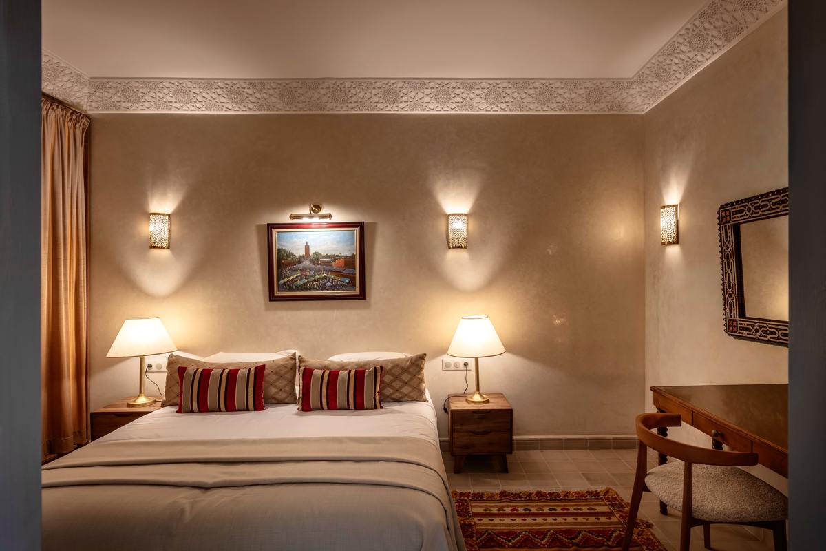 The Patio Room's bed between lantern sconces, beneath a framed painting