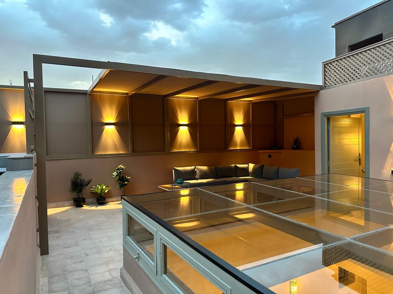 The rooftop lounge in the evening, wall lights washing the alcoves in gold