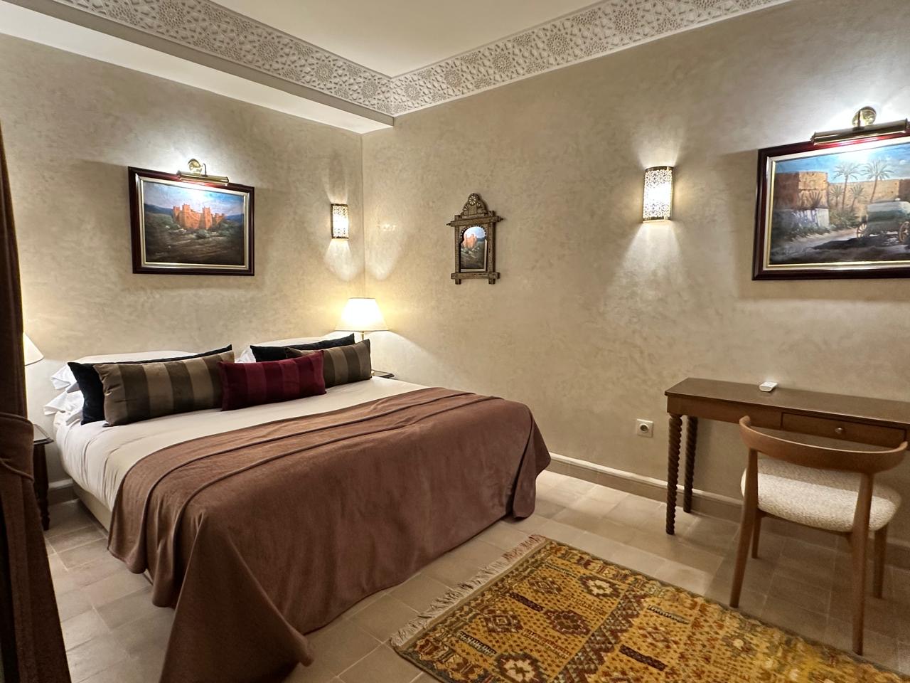 A bedroom with a king bed beneath a moulded plaster cornice