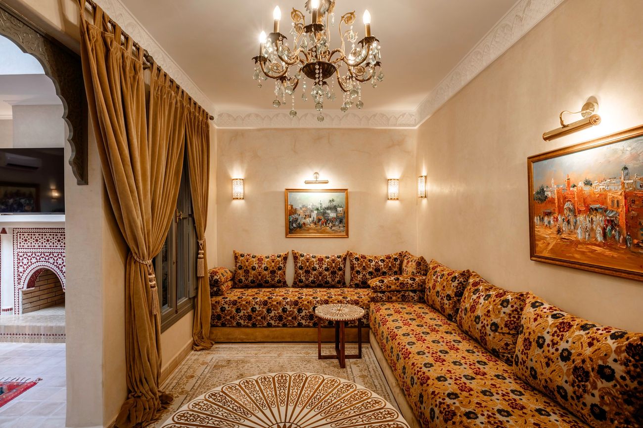 The Moroccan salon: banquettes along two walls beneath a crystal chandelier and painted scenes of the old city