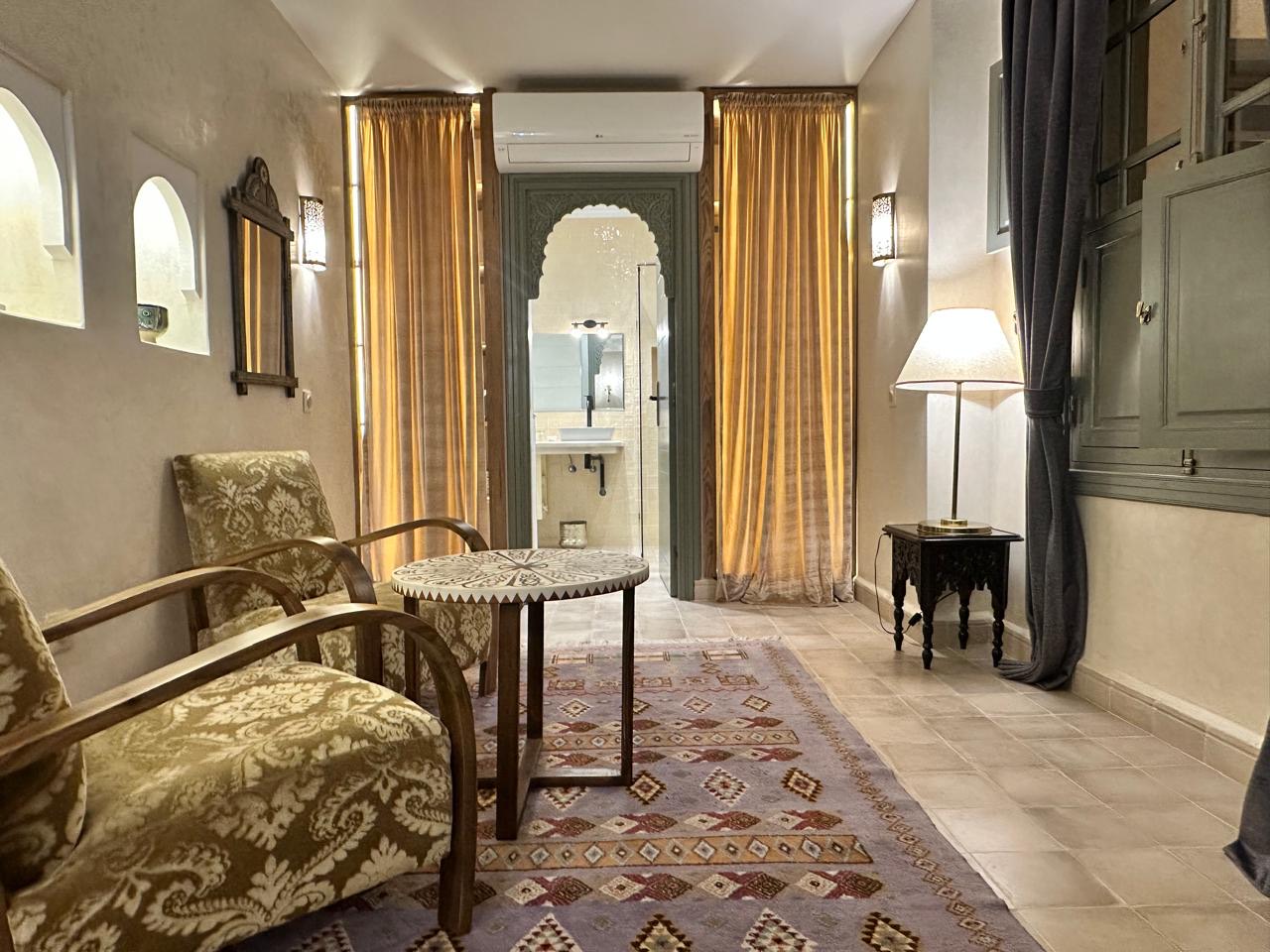 The suite's sitting room, with Deco armchairs and the bathroom through a carved arch