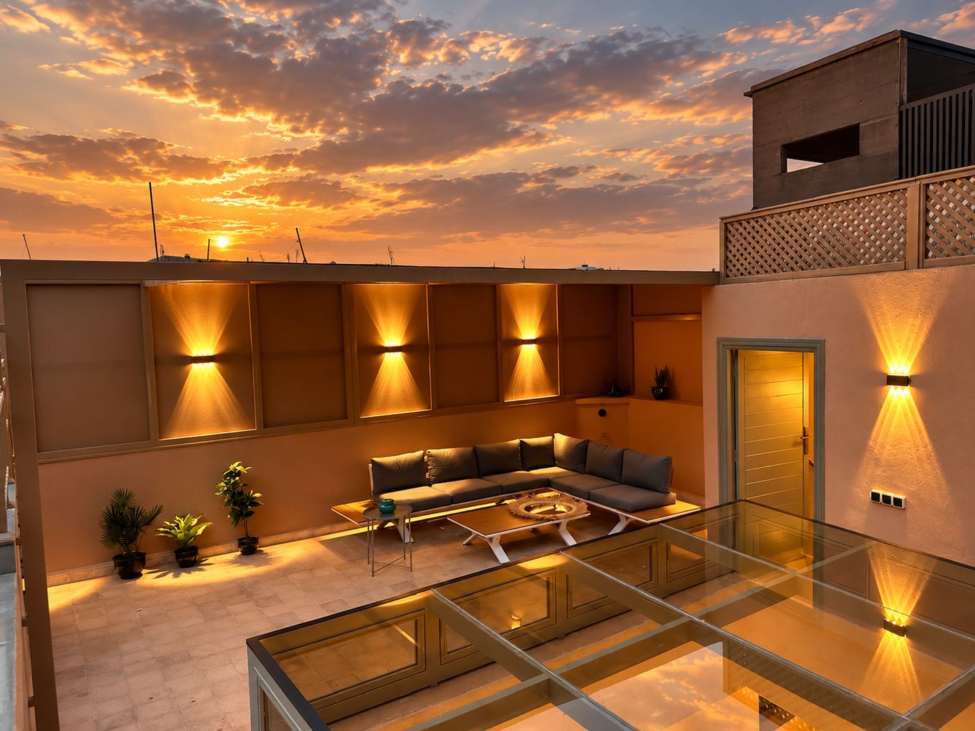 The rooftop at sunset, the lounge lit beneath an open sky with the glass roof of the patio in the foreground